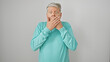 Surprised senior man covering mouth with hands against a white background, portrait