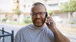 © Krakenimages.com - Handsome, bearded caucasian man confidently chatting on his smartphone, positively absorbed in the fun and sunny city street outdoors, portraying a casual, cool lifestyle with warm smile