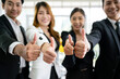 Close up of a group of diverse businesspeople showing raised thumbs at the camera. Recommendation of good choice. The diversity of African and Caucasian businesspeople gives a positive response.