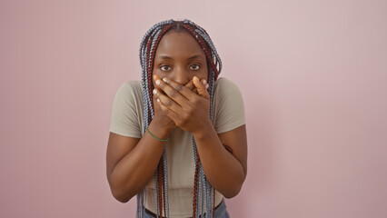 african american woman with braids wearing casual attire posing against a pink background, covering 