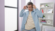 © Krakenimages.com - Young hispanic man listens to music, dancing joyfully indoors at home with a confident smile