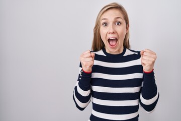 Canvas Print - Young caucasian woman wearing casual navy sweater celebrating surprised and amazed for success with arms raised and open eyes. winner concept.