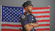 © Krakenimages.com - Confident african american male police officer with arms crossed in front of an american flag indoors.