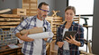 © Krakenimages.com - Two professional carpenters, a man and woman, together using a touchpad while holding blueprints at their carpentry business, a lively duo revolutionizing the woodworking industry!