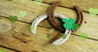 Image of st patrick's shamrock, horseshoe and green hearts on wooden background