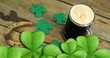 Image of st patrick's day shamrock and glass of beer on wooden background