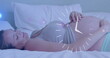 Fast moving clock over happy pregnant caucasian woman lying on bed rubbing belly