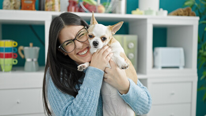 Canvas Print - Young hispanic woman with chihuahua dog hugging siting on the table at dinning room