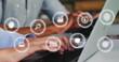 Image of multiple icon in circles over diverse coworkers using laptop and cellphone in office