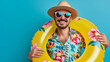 © Vladimir - Front View Cheerful Man Ready for Summer. Cheerful young man in summer hat and sunglasses holding an inflatable ring, ideal for vacation-themed designs.