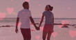 Multiple pink hearts floating against african american couple holding hands and walking on the beach