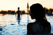 Vacation romance, fling or flirt. Woman and man in pool at sunset in hotel resort. Caribbean paradise. Bad holiday or travel problem. Cheating, infidelity or conflict. Tourist with stress.