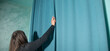 Woman correcting curtain at home.