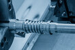The  CNC lathe machine forming  cutting the metal  screw shaft parts in the light blue scene.