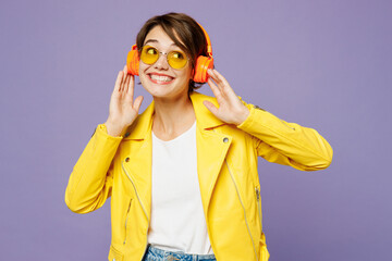 Wall Mural - Young fun smiling woman she wears yellow shirt white t-shirt casual clothes glasses listen to music in headphones look aside on area isolated on plain pastel light purple background Lifestyle concept