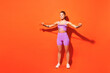 Full body fun young fitness trainer instructor sporty woman sportsman wear purple top clothes in home gym hold elastic rubber band isolated on plain orange background. Workout sport fit abs concept.