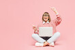 Full body elderly IT woman 50s years old wear sweater shirt casual clothes glasses sits work hold use laptop pc computer point finger aside isolated on plain pink background studio. Lifestyle concept.