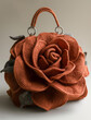 A mini handbag shaped like an oversized rose, made of crochet fabric with visible stitching and texture