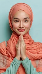 Wall Mural - Radiant asian muslim woman smiling, wishing eid mubarak on pastel background with copy space