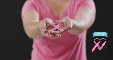 Wall Mural - Breast cancer awareness text banner against mid section of woman holding a pink ribbon