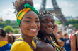 A young woman and man are smiling for the camera in front of the Eiffel Tower. The woman is wearing a yellow shirt and a green and yellow headband