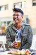 Smiling man enjoying craft beer at a city pub. A candid scene of urban relaxation and the simple pleasures of life.