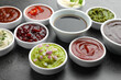 Different tasty sauces in bowls on grey table, closeup