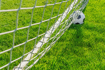 Wall Mural - textured soccer game field with close-up ball in front of the soccer goal - soccer ball in soccer net.