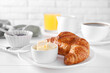 Fresh croissant and butter on white wooden table. Tasty breakfast