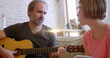 Image of light flashing over caucasian father playing guitar and singing to daughter
