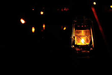 A lamp hanging in the rural, public park in the dark. Close-up of a lamp with black background. Lighting in the dark.