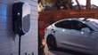 Modern electric vehicle is being charged from a wall box. Generative AI.