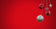 Image of hanging baubles, star and gift box swinging against red background