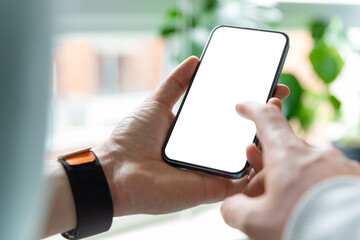 Wall Mural - A man is using a smartphone with a blank, frameless  screen in a contemporary home or office interior. Bright light with plants in the background