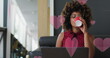Image of pink hearts over biracial businesswoman using laptop
