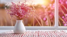   A Vase, Filled With Pink Blooms, Sits Atop A Checkered Tablecloth Beside A Window Sill