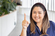 Happy smiling middle aged asian woman pointing 1 fingers up, concept of one point, number one