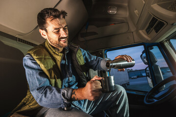 Wall Mural - Young handsome man driving long vehicle and drinking coffee so he could get some energy.