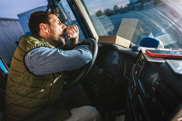 Wall Mural - A tired truck driver takes a break from driving and rests in his truck