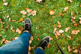 Fototapeta Na drzwi - men legs standing on grass field covered with autumn oak leaves