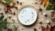 A dramatic white plate on a light wood table surrounded by scattered natural elements like leaves and stones, blending indoors with nature