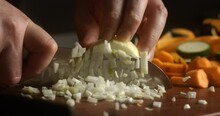 Super Slow Motion Macro Of Fresh Bio Organic White Onion Is Being Cut In Slices By Chef With Sharp Blade Knife On Wooden Cut Board While Preparing Vegetarian Salad Dish In Restaurant Kitchen.