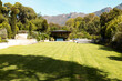 Lush green lawn stretches towards gazebo with mountains in background at home