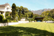 Lush green lawn stretches in front of large house with mountains behind, at home