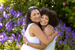 Mother and Daughter, mature biracial woman and young biracial woman hugging in garden at home