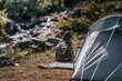 tents pitched on hillsides beside streams of water from waterfalls. hiking bag, hiking shoes on the ground.