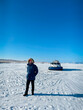 Portrait of the man wearing winter clothes standing by Khivus. Transport on ice. On the surface of the transparent frozen Lake Baikal. Russia. Travel and winter holiday concept