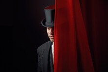 Appearing Handsome Man Magician Peeking Out From Behind Stage Drapery Curtain
