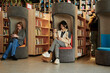 © TrueFrame Collective - Two young intercultural women using smartphones in library or book shop against African American guy standing between shelves