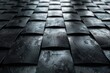 A monochromatic image depicting dark, textured square tiles that give off the appearance of being wet or moist